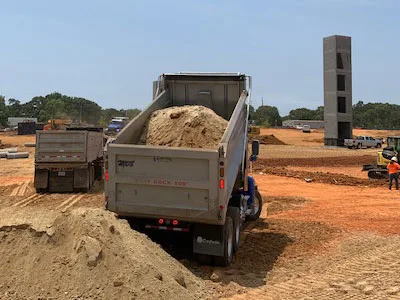 Dump truck unloading fill dirt on a job site